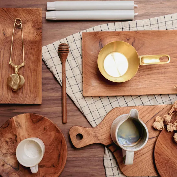 Flat lay of wooden kitchenware, ceramic pitchers, and candles on a plaid cloth