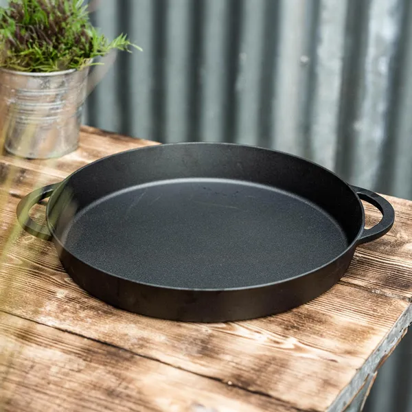 Black cast iron pan with two handles on a rustic wooden table